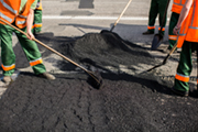 Arbeiter bringen eine Asphaltschicht auf eine Straße auf