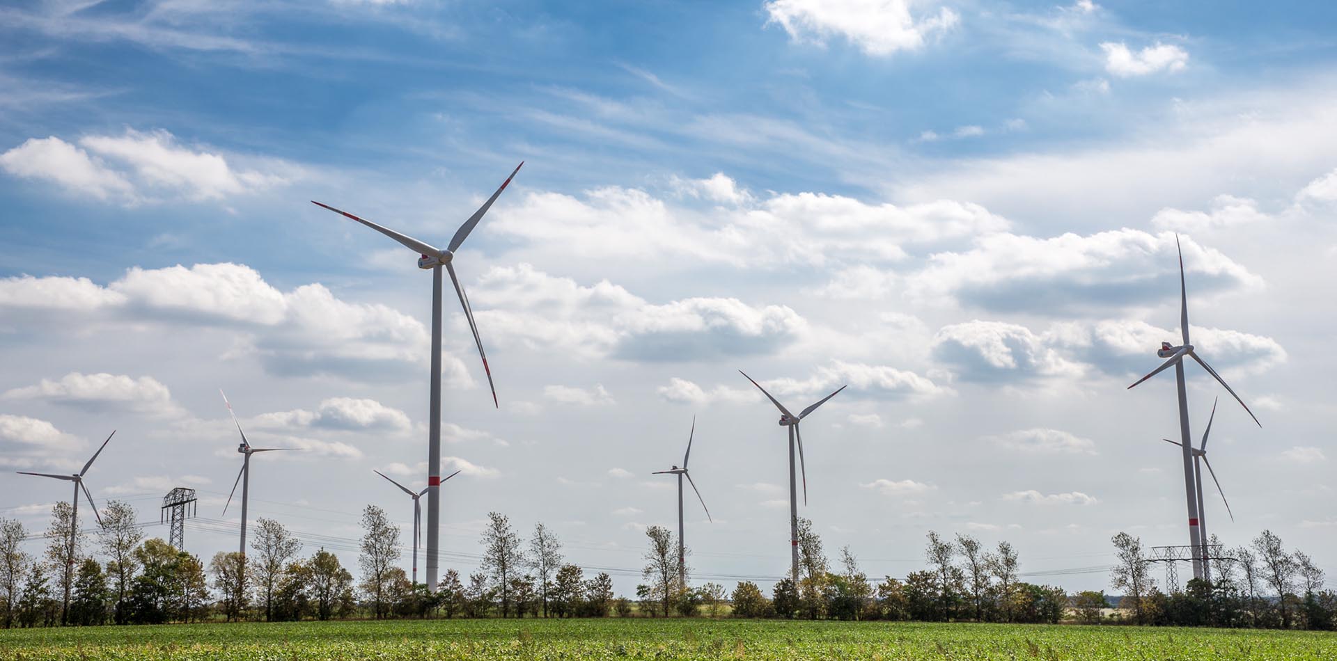 ein Windpark mit acht Windrädern und Strommasten