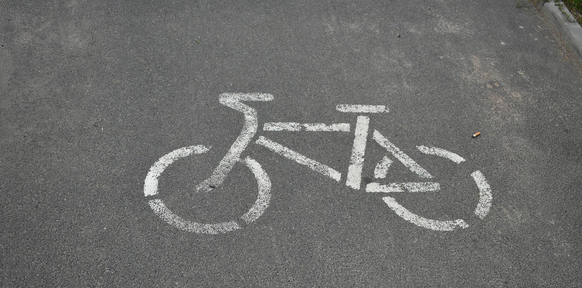 auf einem Radweg ist als Hinweis ein weißes Piktogramm eines Fahrrades aufgetragen
