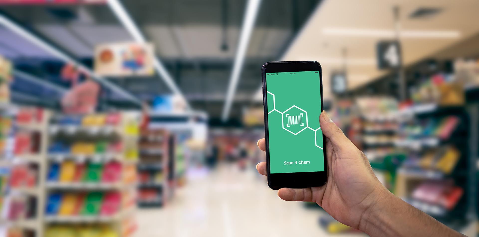 ein Mensch geht durch eine Kaufhalle und hat auf dem Handy die App 'Scan 4 Chem' geöffnet