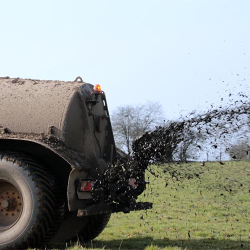 aus einem Tank wird Gülle auf ein Feld aufgebracht